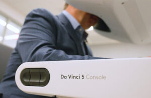 DeviceTalks Editorial Director Tom Salemi operating an Intuitive Surgical da Vinci 5 to perform tasks that demonstrate the surgical robotics system’s capabilities.